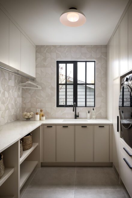 Les électroménagers, intégrés au mur de rangement et installés à une hauteur ergonomique, se fondent dans l'ébénisterie pour créer une salle de lavage épurée. Ébénisterie : Ateliers Jacob | Design + Build : Trickle Creek Designer Homes | Photo : Eymeric Widling