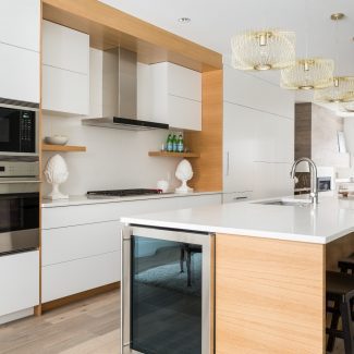 Cuisine moderne blanche avec armoires blanches, îlot central et dosseret blanc.