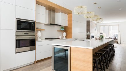 Cuisine moderne blanche avec armoires blanches, îlot central et dosseret blanc.